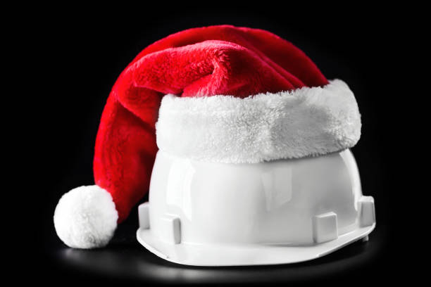 Santa Claus helper hat on white building helmet. Isolated on black background stock photo