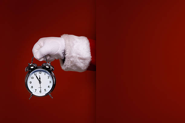 Santa Claus hand with alarm clock over red background