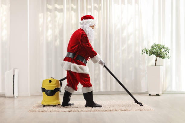 Santa claus using a vacuum cleaner stock photo