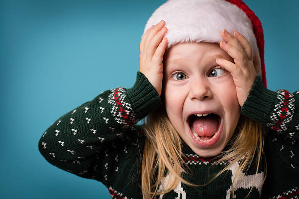 Santa's Stressed Little Helper Wearing Hat and Christmas Sweater Color image of a little girl wearing a Santa hat and an ugly Christmas sweater, with a stressed/overwhelmed  face. ugly girl stock pictures, royalty-free photos & images