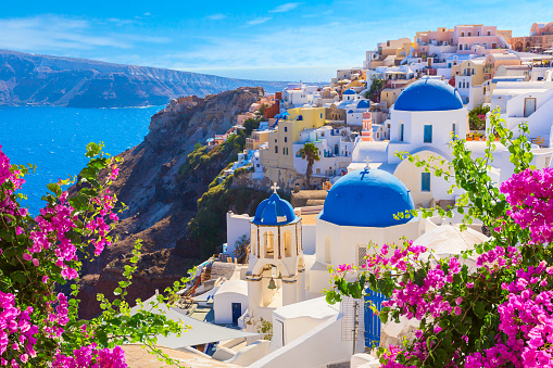 Santorini island, Greece. Oia town traditional white houses and churches with blue domes over the Caldera, Aegean sea.