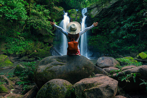 Rear view of young woman in front of Sapan Waterfall, Khun Nan National Park, Boklua District, Nan Province, Thailand.