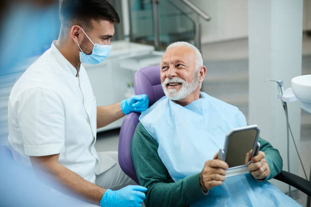 satisfied senior man communicating with his dentist after dental procedure at dentist's office. - tandarts stockfoto's en -beelden