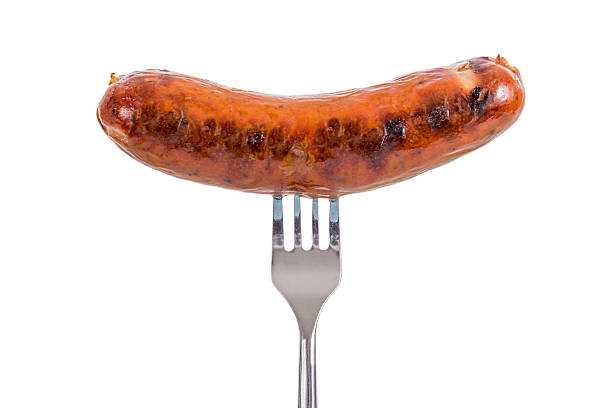 Sausage on a Fork Grilled Sausage on a fork isolated on white background sausage stock pictures, royalty-free photos & images