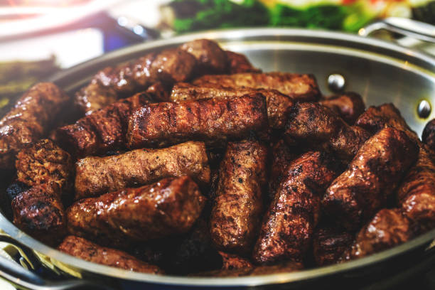 Sausages in bowl, grilled and cooked for the holiday table. Homemade barbecue grill in rustic pan. Delicious Romanian mici or mititei as traditional food. Close up picture with bbq, pork and lamb mixed meat. stock photo