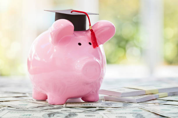 Saving for education and university Piggy bank with a graduation mortar board cap concept for the cost of a college education student loan stock pictures, royalty-free photos & images
