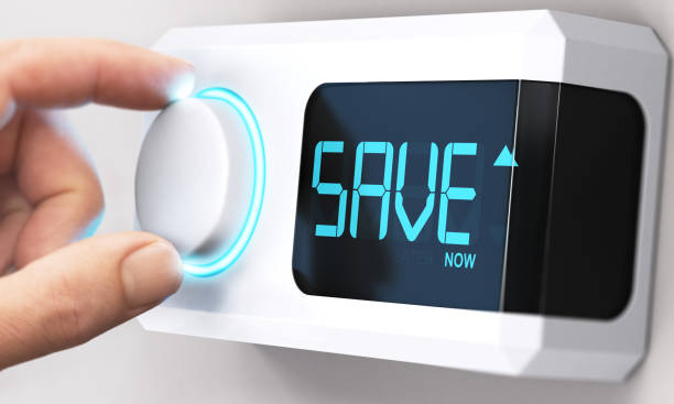 Saving Money; Decrease Energy Consumption Hand turning a thermostat knob to increase savings by decreasing energy consumption. Composite image between a hand photography and a 3D background. energy efficient stock pictures, royalty-free photos & images
