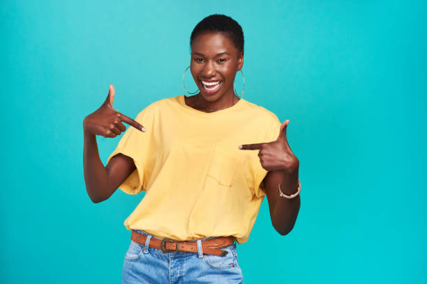 Say it like you mean it Studio shot of a confident young woman pointing at her t shirt against a turquoise background blank t shirt stock pictures, royalty-free photos & images