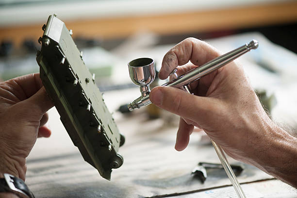 Scale modeling a leisure activity. Man airbrushing a scale model vehicle in a workshop, selective focus on the airbrush. airbrush stock pictures, royalty-free photos & images