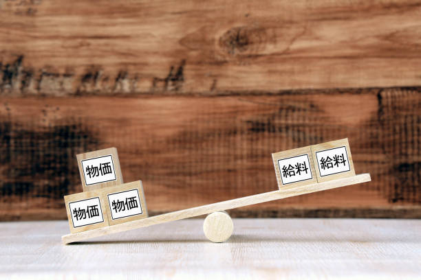 日本語で「生活費」と「給与」の言葉を持つスケールと木製のブロック - 値上げ ストックフォトと画像