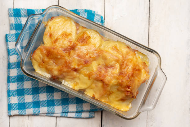 patate smerlate con prosciutto e formaggio su sfondo bianco - capesante gratinate foto e immagini stock