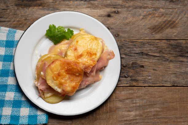 patate smerlate con prosciutto e formaggio su sfondo legnoso - capesante gratinate foto e immagini stock