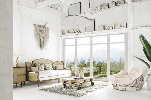 Bohemian living room interior with white and beige colored rattan furniture and wooden elements.