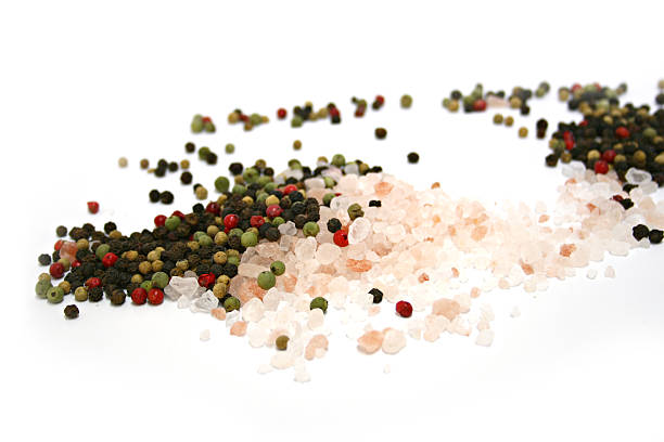 Scattered pile of Himalayan pink salt & mixed peppercorns stock photo