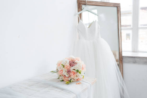 Scenery for the morning of the bride with a white wedding dress and a bouquet. Scenery for the morning of the bride with a white wedding dress and a bouquet.-Image wedding dress stock pictures, royalty-free photos & images