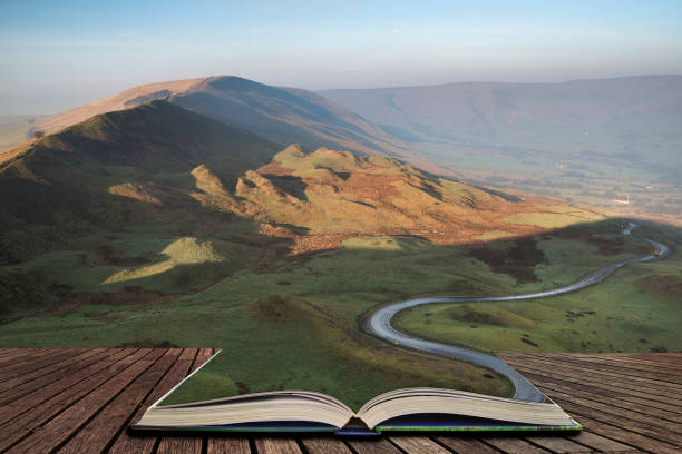 A scenic road winds its way through the Edale Valley on a foggy Winter sunrise in the Peak District in pages of open book, story telling concept stock photo