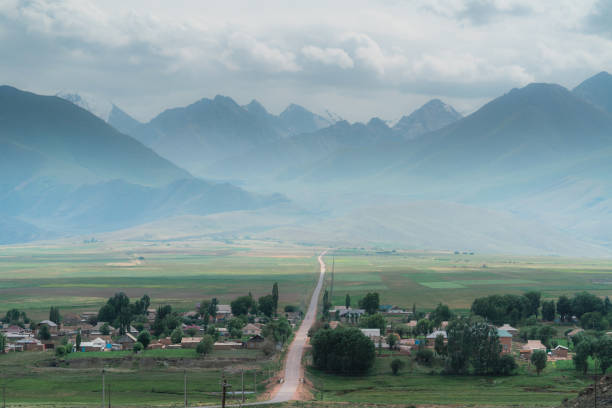 Scenic view of road through the village Tien Shan mountains in Kyrgyzstan in summer Scenic view of hills of  Tien Shan mountains in Kyrgyzstan in summer tien shan mountains stock pictures, royalty-free photos & images