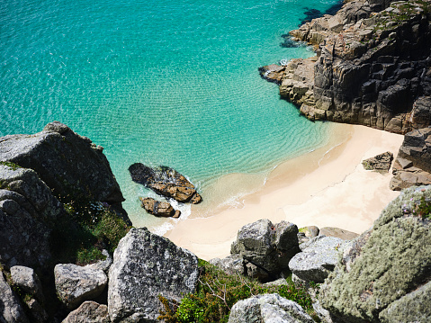 Scenic views downwards onto an empty idyllic beach between Pedn Vounder and Porthcurno, South Cornwall on a sunny June day.