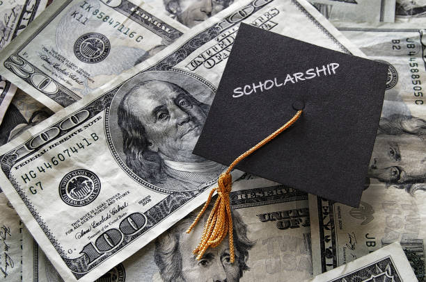 Scholarship graduation cap on cash stock photo