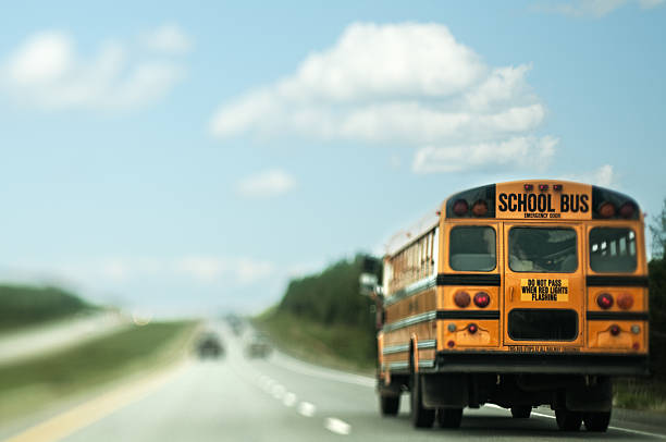 School Bus A school bus traveling down a highway.  Photographed with a tilt-shift lens. school bus driver stock pictures, royalty-free photos & images