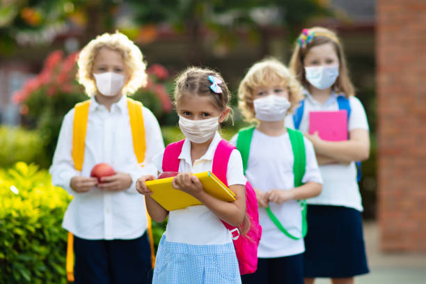 School child wearing face mask. Virus outbreak. School child wearing face mask during corona virus and flu outbreak. Boy and girl going back to school after covid-19 quarantine and lockdown. Group of kids in masks for coronavirus prevention. school building stock pictures, royalty-free photos & images