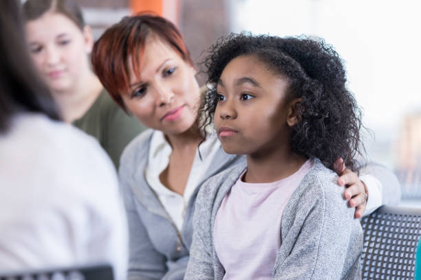 School counselor comforts student School counselor comforts elementary age student while in group therapy session. school counselor stock pictures, royalty-free photos & images