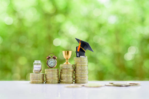 School funding, saving for higher education concept : Black graduation cap, campus diploma, trophy cup of success, a clock, a saving jar on stacks of increasing coins. School funding, saving for higher education concept : Black graduation cap, campus diploma, trophy cup of success, a clock, a saving jar on stacks of increasing coins. free degree stock pictures, royalty-free photos & images
