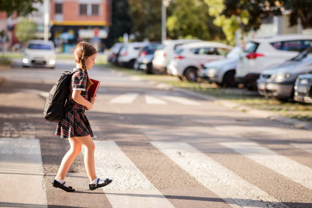 School girl on pedestrian crossing Child crossing the street on her way to school crosswalk stock pictures, royalty-free photos & images