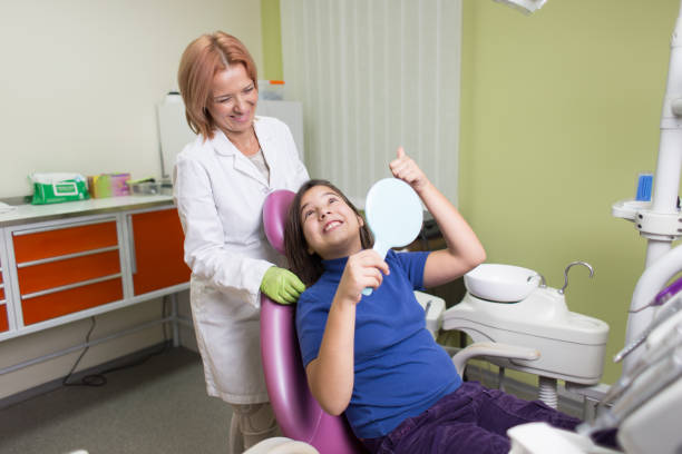 School girl sitting on dental chair while having dental treatment. stock photo