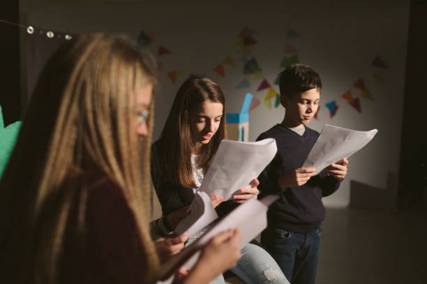 School Play Rehearsal Group of children enjoying drama club rehearsal. They are reading script. young male actors stock pictures, royalty-free photos & images