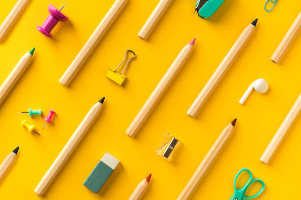 Diagonally arranged school supplies and coloring pencils  on yellow background. Back to school colorful flat lay