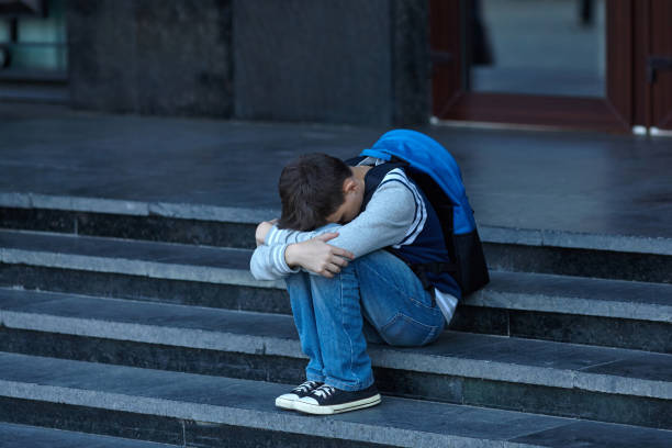 Schoolboy crying in the yard of the school Schoolboy crying in the yard of the school. Negative emotion. bullying stock pictures, royalty-free photos & images