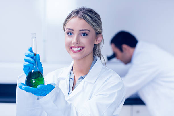 Science student holding green chemical in beaker at the university