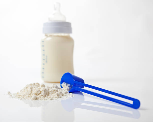 Scoop and Bottle A close-up shot of baby milk formula with a plastic measuring spoon and bottle. baby formula stock pictures, royalty-free photos & images