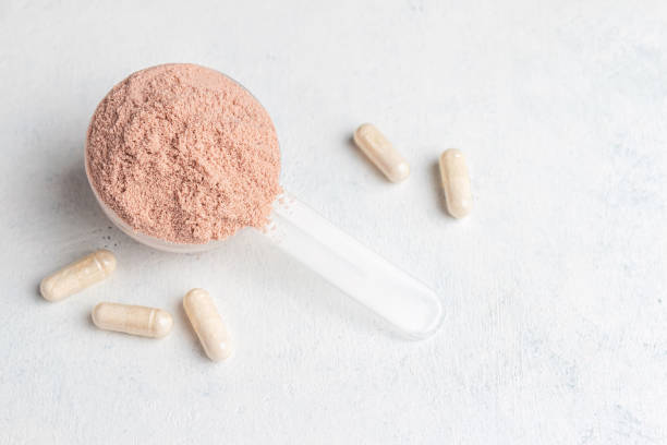 Scoop of whey or soy protein isolate, white capsules of amino acids and creatine, bodybuilding food supplements on white table background with copy-space Scoop of whey or soy protein isolate, white capsules of amino acids and creatine, bodybuilding food supplements on white table background with copy-space. glucosamine stock pictures, royalty-free photos & images