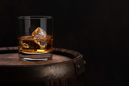 Scotch whiskey glass and old wooden barrel. With copy space