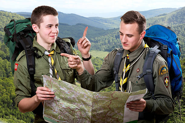 Scout tour Two young scout boys with backpacks holding the map and showing the right way traveling in the mountains scout camp stock pictures, royalty-free photos & images