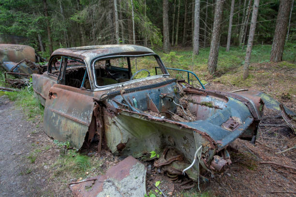 Scrap yard with old cars in forest in Ryd, Kyrko Mosse in Sweden stock photo