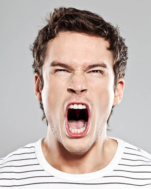 Scream Portrait of frustrated young man screaming at the camera. Studio shot. mouth open stock pictures, royalty-free photos & images