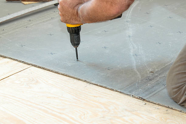 Screwing cement board to the subfloor stock photo