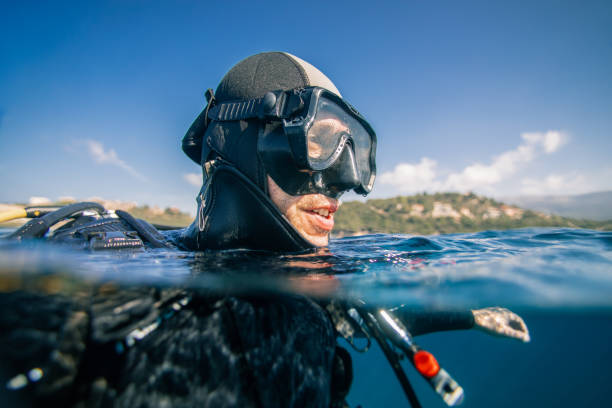 Scuba diver at sea surface Portrait of scuba diver at sea surface preparing for dive underwater. aqualung diving equipment photos stock pictures, royalty-free photos & images