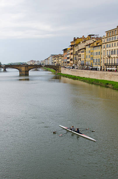 Sculling on the Arno River in Florence, Italy Florence, Italy - April 17, 2015: Florence, Italy is known as the birthplace of the Renaissance.  Founded in 80 B.C. by Lucius Cornelius Sulla as a settlement for his soldiers, it was named Fluentia, which later became Firenze.  Renown artists like Michelangelo, Leonardo da Vinci, Botticelli and Donatello all lived, studied and worked in Florence, along with architects like Brunelleschi, who designed the dome of the city's duomo, Cattedrale di Santa Maria del Fiore.  Florence has a colorful history as a political and financial center, dominated for over 150 years by the Medici family and is also known as a fashion center.  Today, it's rich heritage in art can be enjoyed at several galleries and museums including the Uffizi and the Gallerie dell'Accademia, as well as the Pitti Palace (Palazzo Pitti).  Pictured here is a scull with two crew members, propelling their boat up the Arno River in the heart of Florence. botticelli stock pictures, royalty-free photos & images