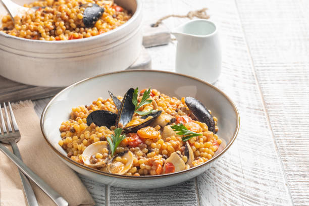 Seafood pasta. Fregula with seafood on a white wood surface. stock photo