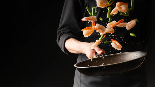 seafood, professional cook prepares shrimps with sprigg beans. cooking seafood, healthy vegetarian food and food on a dark background. horizontal view. eastern kitchen - chef imagens e fotografias de stock