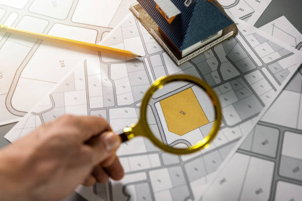 searching building plot for family house construction - hand with magnifier on cadastre map  Location and property stock pictures, royalty-free photos & images