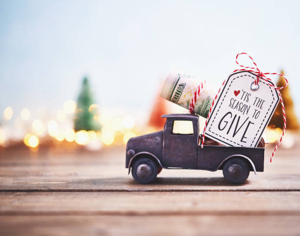Season to Give. Truck carrying roll of dollars with holiday background
