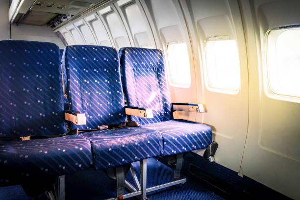 Seats in commercial aircraft cabin with sun light shining through the windows  airplane seat stock pictures, royalty-free photos & images