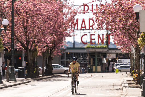 Seattle, USA – April 13, 2020: Late in the day a person on a Bicycle, with Pike Place Market in the background.
