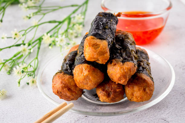Seaweed Chicken Roll are stacked on a glass plate with chopsticks and sweet chilli sauces. stock photo