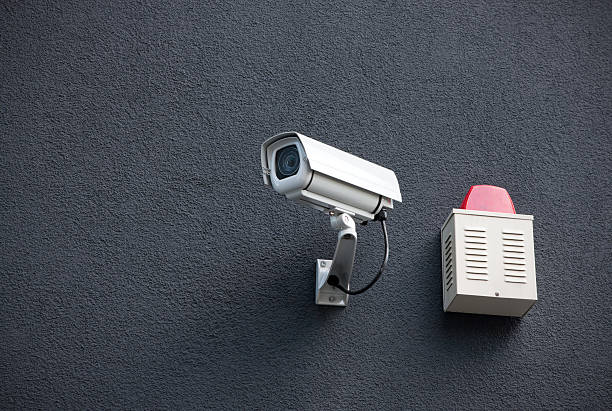 Security camera and alarm box on a black wall stock photo